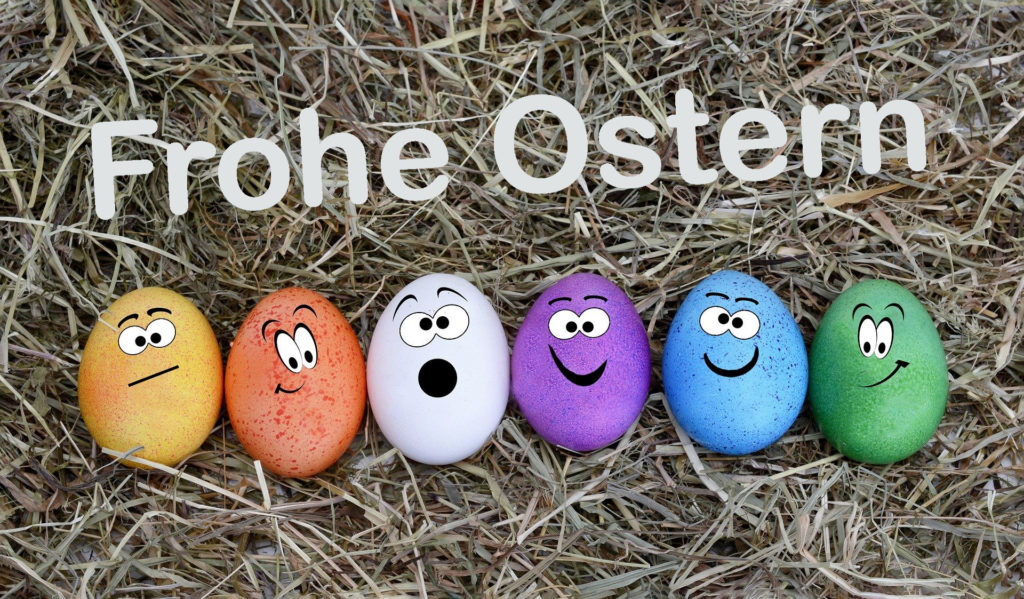 Bunter Eier mit Gesichter im Stroh für frohe Ostern